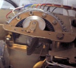 The clock is hardwired for a 24-hour display format. This stepper relay keeps track of the hour. It's a 4 pole, 24 throw. It's got two sets of moving contacts - the set not currently on the semicircle of fixed contacts is visible hanging out the side.
