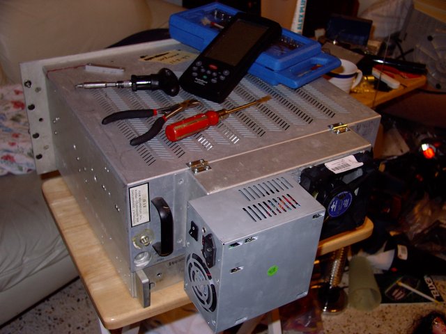 The back of the case. The protruding aluminum part below the power supply (which would not fit inside due to the presence of a middle shelf thing, now the motherboard shelf), is a frame that once held a pair of 120mm Muffin fans. Since I'm not going to be putting 45 vacuum tubes back into it... the cooling requirements are far less strenuous. The old fan frame now flips up on hinges to reveal the ATX back panel and slots, and a gap cut in its bottom allows cables to go through.