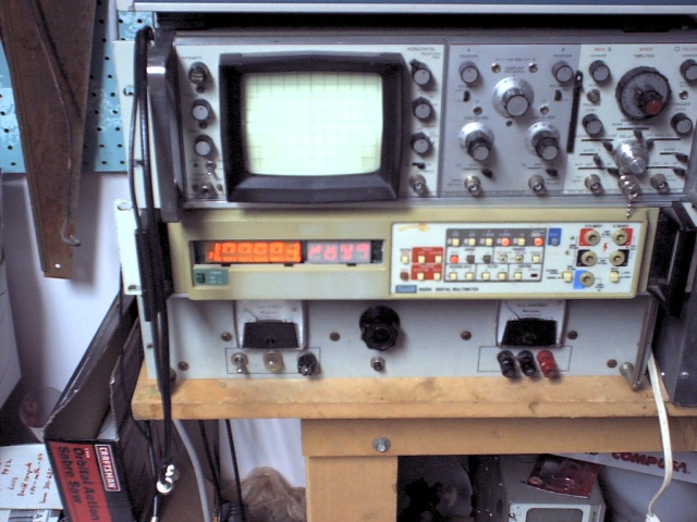 The most presentable part of my workroom. You do NOT want to see anything else. Trust me. Really. From top, old HP 60Mhz 'scope, Fluke 8520A (running its downright hypnotic display self-test), old power supply capable of, for no particularly good reason, about 48 volts @ 10 amps.